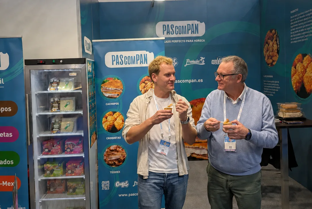 Dos miembros del equipo de Pascompan charlan mientras prueban sus productos en el stand de feria